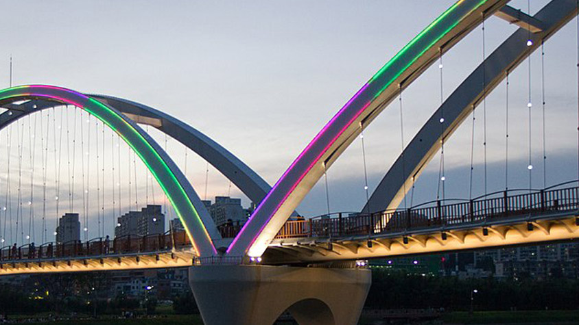 Illuminated modern bridge in Ulsan during dusk for the Ulsan-Barcelona Technology Exchange Academic Event: "Connecting the Legacy of Great Innovators" with the Gaudí World Foundation.